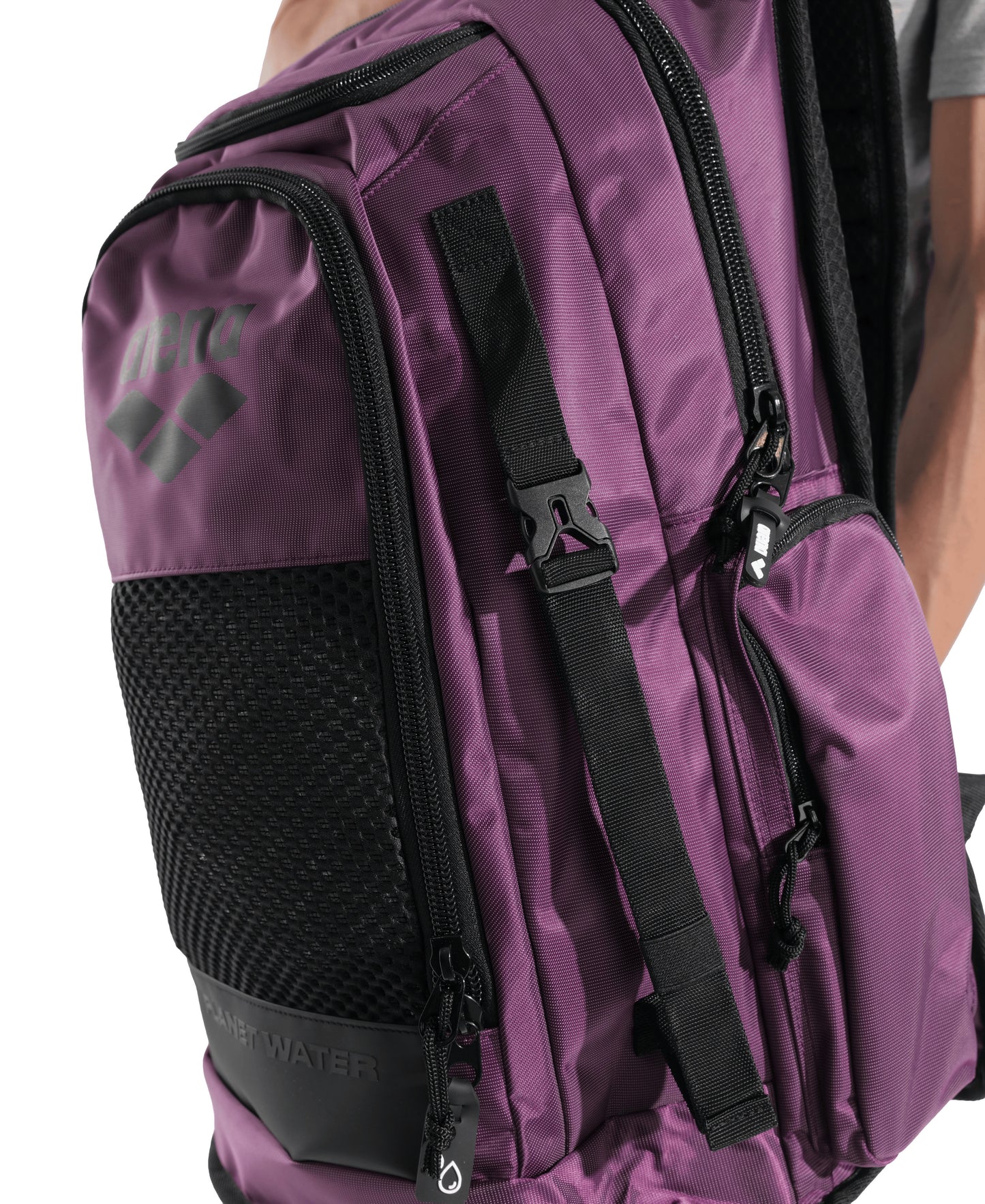A close-up of a person wearing the Arena All Set Sports Swim Backpack 45L in plum, featuring black straps, mesh pocket, visible zippers, a water-repellent finish, and the Arena logo with "WATER" on the side.