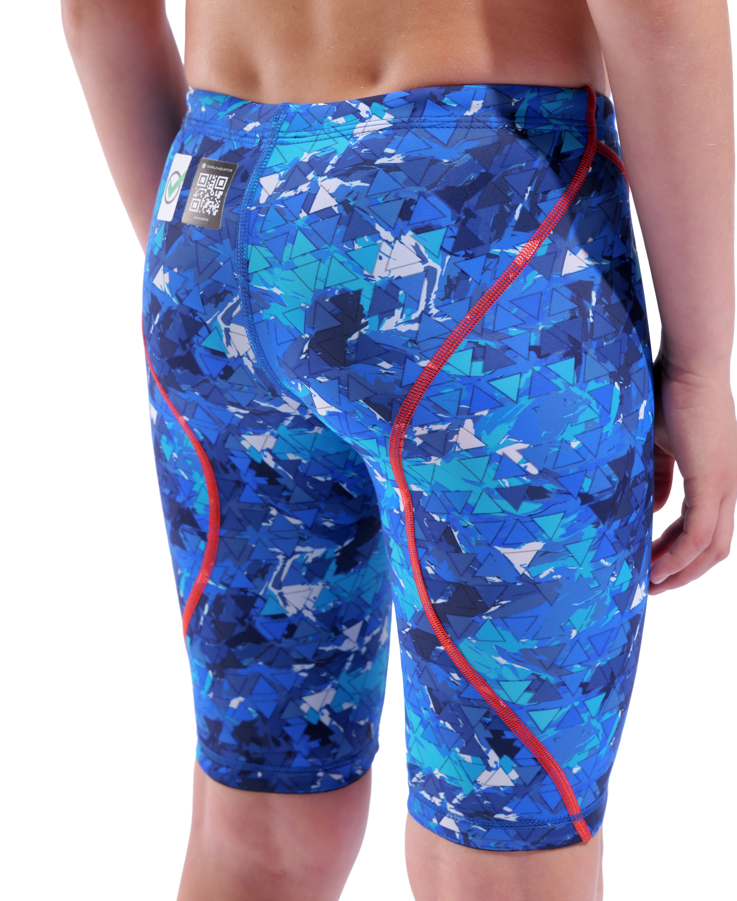 A boy wears the Arena Boys Powerskin ST Next Jammer - Limited Edition - Splashy by Arena. The eco-friendly swimwear features blue abstract geometric patterns, red seams, and a small rectangular tag near the waistband, shown from the back.