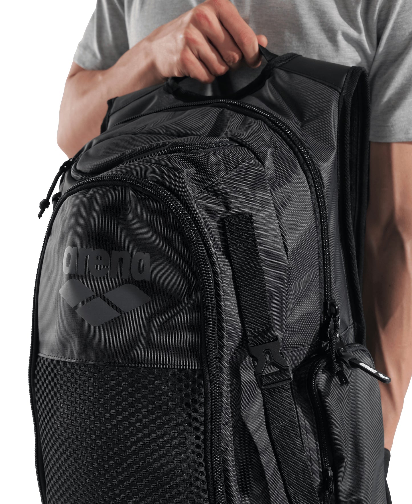 A person in a gray shirt holds the Arena All Set Sports Swim Backpack 45L by Arena, featuring multiple zippered compartments, a mesh front pocket, and an integrated wet management system.